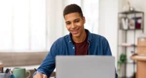 Jeune homme qui est heureux d'écrire sa lettre de motivation pour être animateur